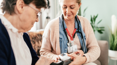female health worker taking blood pressure for senior woman