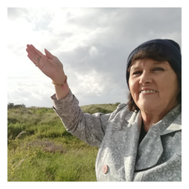 Image of a learner standing in nature with her hand in the air