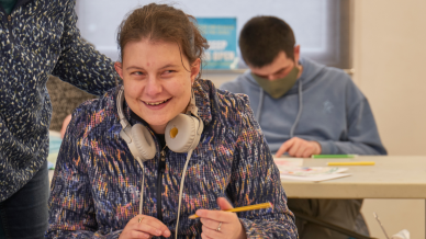 smiling young woman with headphones around neck working on some learning materials