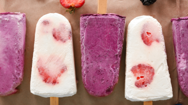 A row of homemade alternating blueberry ice lollies and strawberry and banana ice lollies